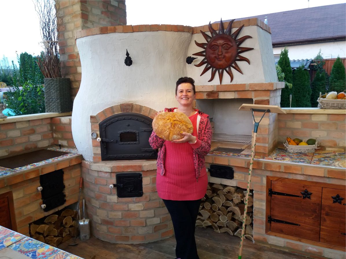 Domáci chlieb upečený v peci na drevo Pecmaniak držiaca žena v záhradnej kuchyni