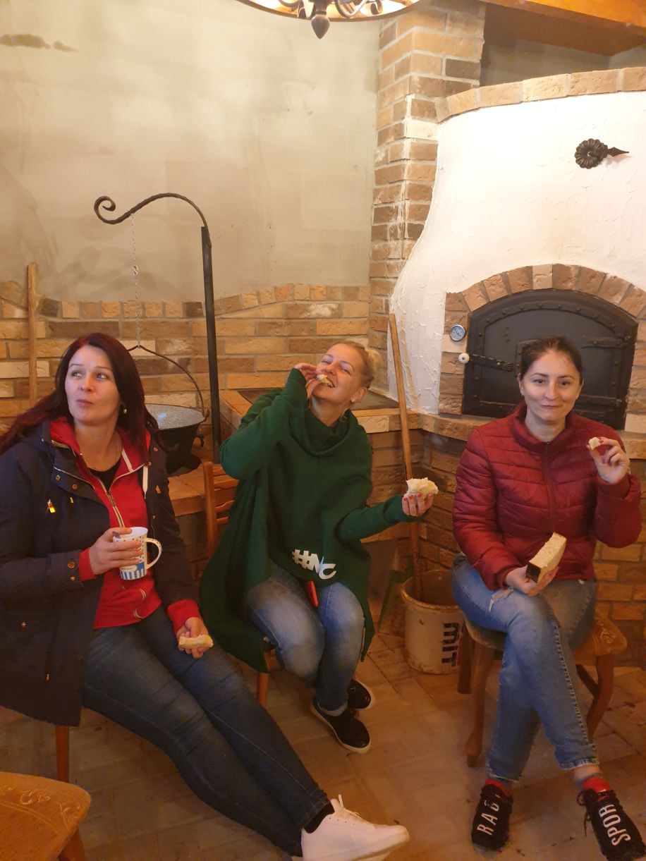 Priatelia sedia v záhradnej kuchyni pri peci Pecmaniak a vychutnávajú si jedlo